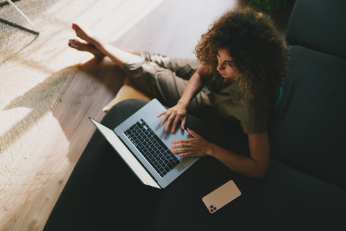 femme surbookée devant son bureau avec un croissant en bouche